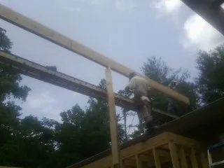 Carpenter setting a ridge beam over a new addition frame — Ice Dam Removal by Roofing Brothers in Allgood
