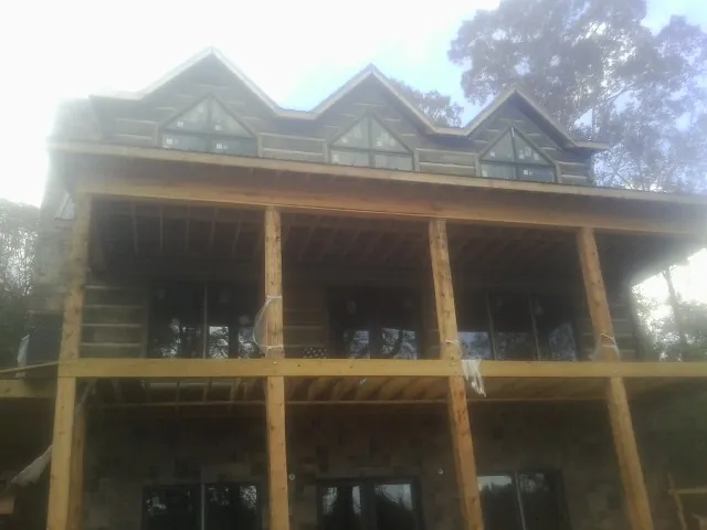 Dormers and porch framing on a large log home under construction — Roof Coating work by our crew in Allgood