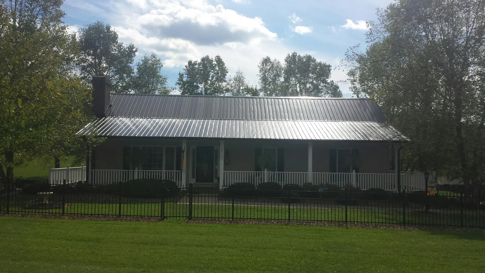 Gray metal roof on a brick ranch with a full width front porch — Gutter Guard Installation work by our crew in Allgood
