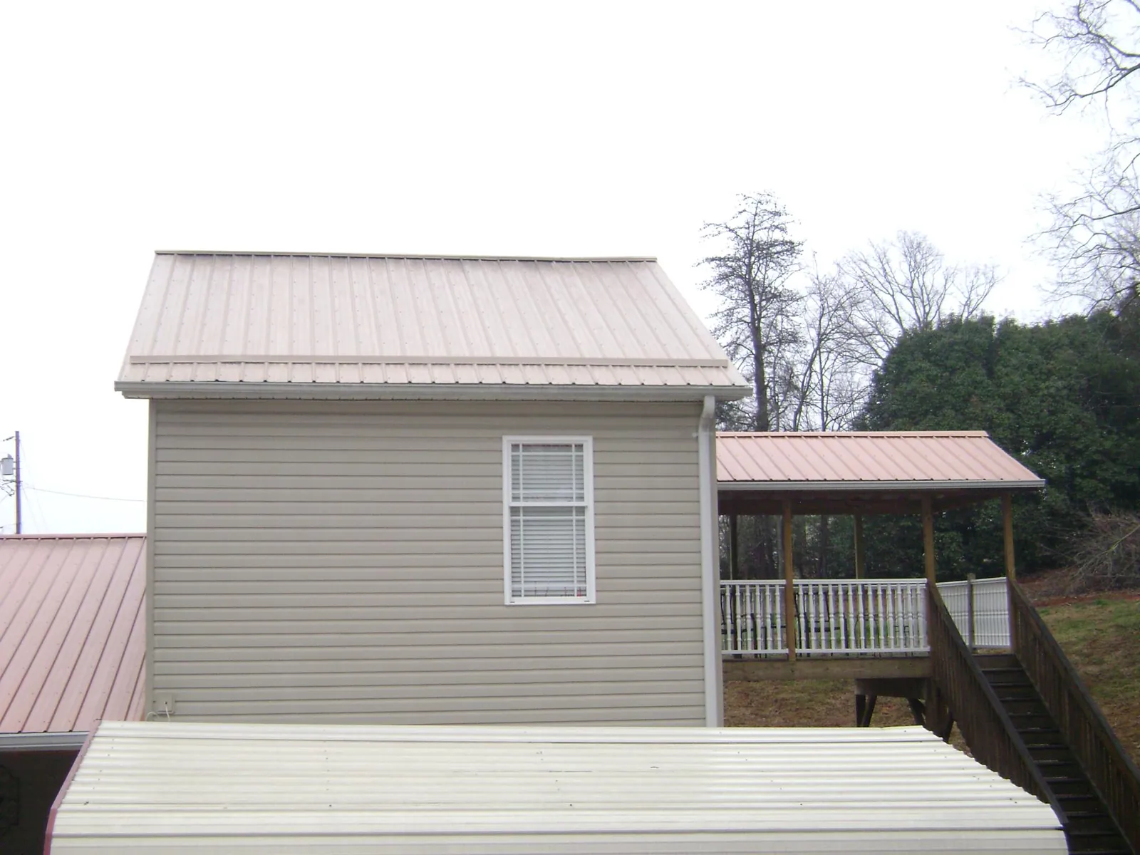 Tan metal roofs on a two story addition and attached porch, from a Roof Replacement job in Allgood