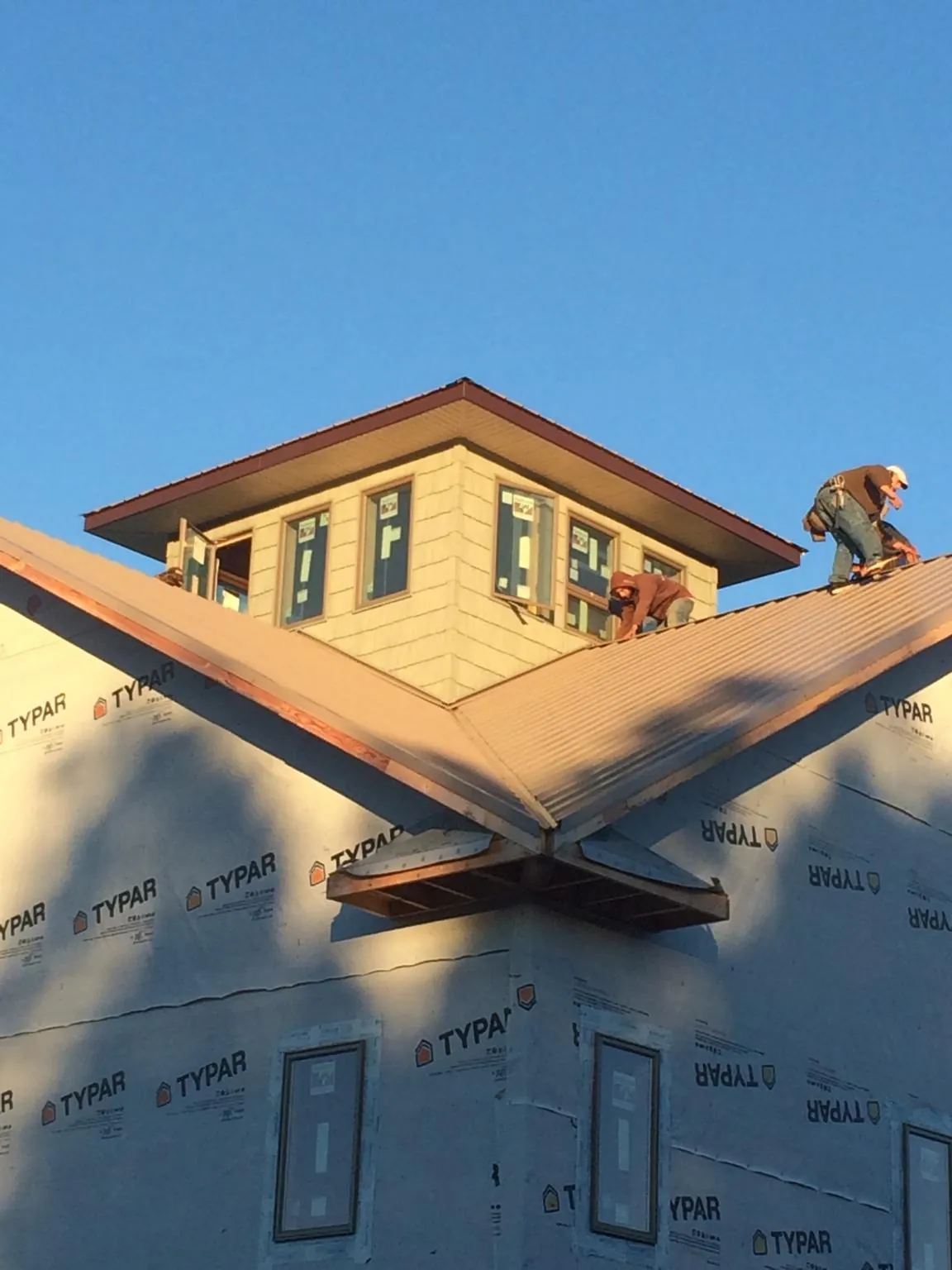 Roofers working around a rooftop cupola on a new metal roof at sunset — Roof Waterproofing in Allgood by Roofing Brothers